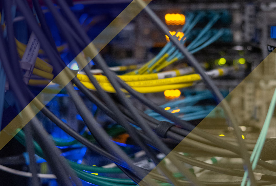 Close-up of bundled network cables in a server rack, with yellow and blue lines crossing the frame and glowing indicator lights in the background.