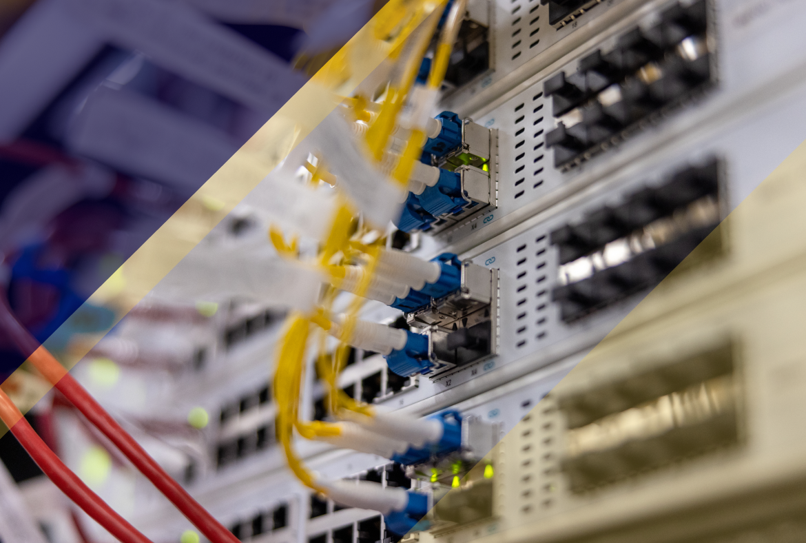 Close-up of network equipment with fiber cables connected to switches, blue and yellow connectors visible, and green indicator lights glowing in a server rack.