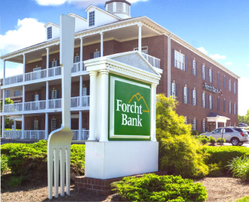 Brick Forcht Bank building with white columns and balconies, green Forcht Bank sign, and a large white fork sculpture in front.