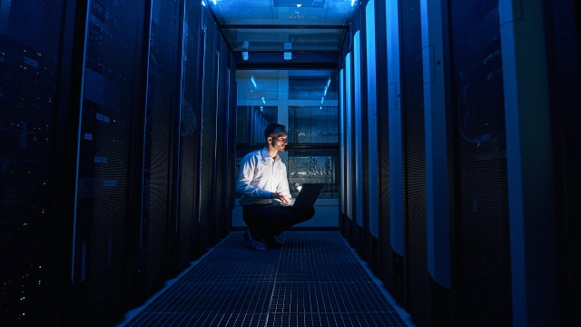 individual looking at a laptop in a server room