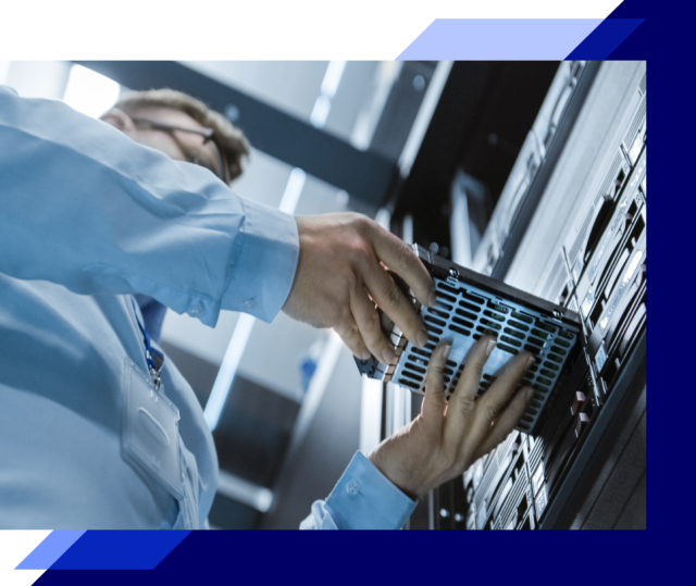 Hands installing a server component into a rack, showing close-up maintenance work inside a data center environment