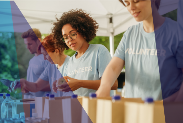 Volunteers in matching shirts pack boxes and supplies at an outdoor table with water bottles lined up, under a canopy with soft blue overlay graphics