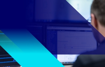 Abstract blue and teal overlay shapes over blurred office scene with a person working at a computer screen in the background