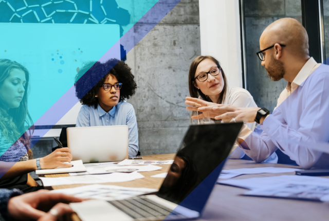 Team members collaborating around a conference table with laptops and documents, accented by blue geometric overlays in a modern office.