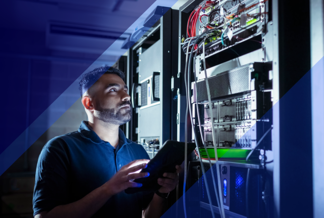 Technician using a tablet while inspecting server racks and network equipment in a data center, with blue geometric graphic overlays