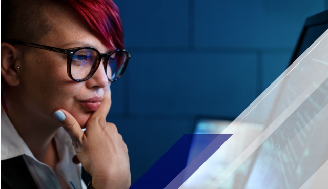 Close-up of a person with red hair and glasses focused on a computer screen, with blue and white geometric overlays and digital graphics.